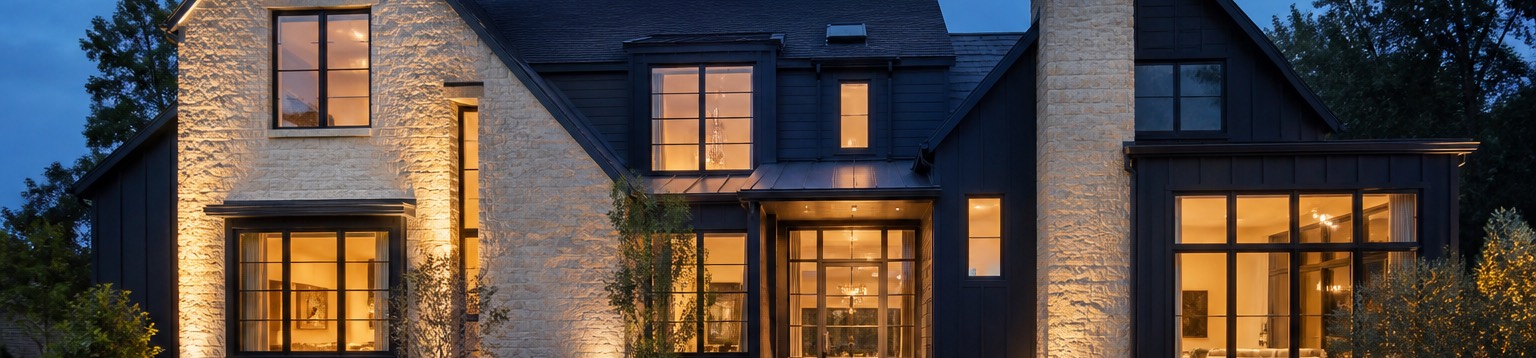 An American home at blue hour with warm light glowing through every window