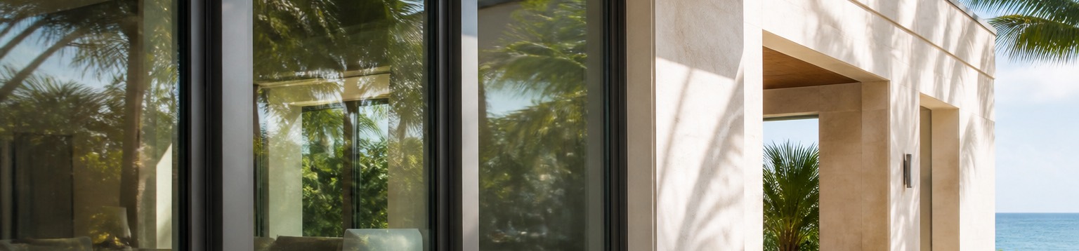 A coastal home facade with heavy impact-rated windows and thick laminated glass